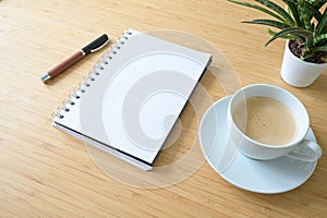 Blank spiral notepad, coffee cup, pen and a plant on a desk made of bamboo wood, business or home office concept, mockup, copy