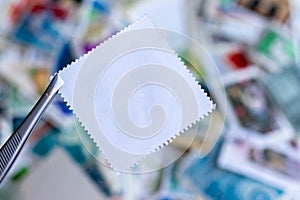 Blank square postage stamp against blurred background collection of multicolored postage stamps of different countries