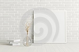 Blank square poster frame mock up standing on white floor next to white brick wall with vase and books. Clipping path around poste