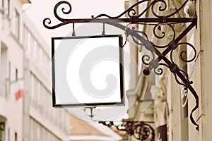 Blank square signboard, hanging from wrought iron bracket