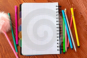 Blank squared notebook with colorful felt tip pens and pencils on wooden desk