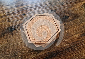 Blank stack coaster mockup with cork texture on wooden surface. Hexagonal drink pad pile template