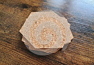 Blank stack coaster mockup with cork texture on wooden surface. Hexagonal drink pad pile template