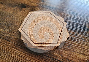 Blank stack coaster mockup with cork texture on wooden surface. Hexagonal drink pad pile template