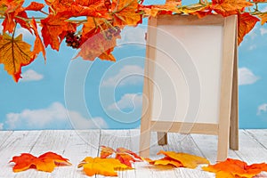 Blank standing whiteboard on weathered wood with fall leaves