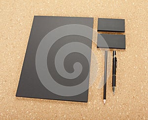 Blank Stationery on cork board. Consist of Business cards, A4 letterheads, pen and pencil.