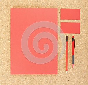 Blank Stationery on cork board. Consist of Business cards, A4 letterheads, pen and pencil.