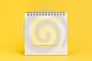 Blank sticky note with copy space to put text on desktop calendar on yellow background using as reminder, important message or mem