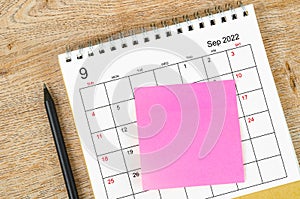 Blank sticky note on September 2022 desk calendar on wooden background for your text