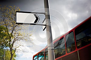 Blank street sign with red bus behind