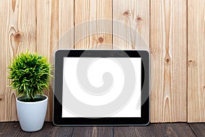 Blank tablet computer and little tree or flower bouquet in white vase on wood background with copy space