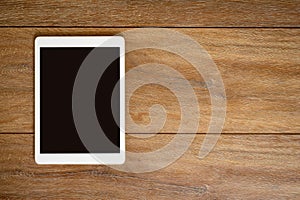 Blank Tablet computer on wood table background with space for te