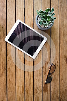 Blank tablet on wooden desk with sun glasses
