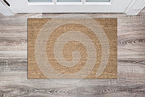 Blank tan colored coir doormat before the white door in the hall. Mat on wooden floor, product Mockup