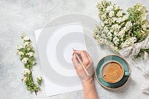 Blank for text, morning black coffee, and bouquet white spring flowers. Top view. Spring. Female hand writing