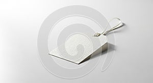 A blank, textured, white paper tag with a string loop is resting