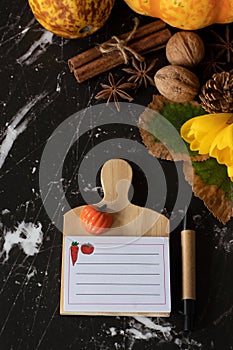 Blank Thanksgiving note and pen on a dark background with autumn fruit, flower, and leaves, vertical shot