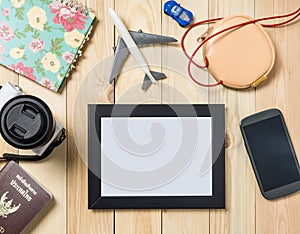 Blank Travel Picture frame on wooden table with travel items.