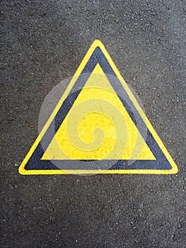 Blank triangle hazard, attention, warning, danger sign on the black asphalt