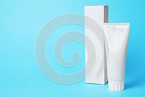 Blank tube of toothpaste and box on color background.