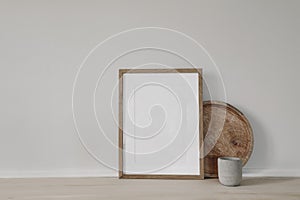 Blank vertical picture frame mockup. Poster display. Round wooden tray, concrete candleholder on working table, desk