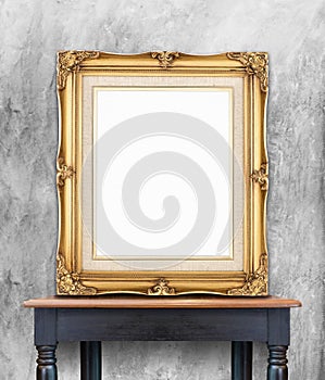 Blank vintage golden photo frame lean at gray color concrete wall on wood table