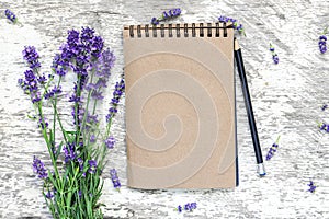 Blank vintage notepad with lavender flowers bouquet and pencil over white wooden table. top view. mock up