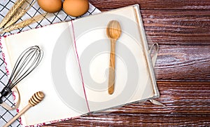 Blank vintage recipe book, eggs and spoon on the wooden background. Top view. Place for text. Banner