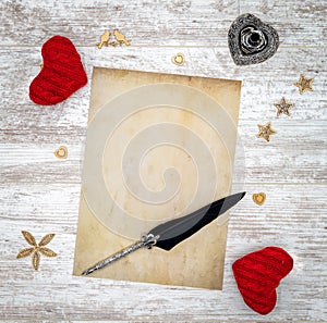 Blank vintage Valentine`s Day card with red cuddle hearts, wooden decorations, ink and quill - top view