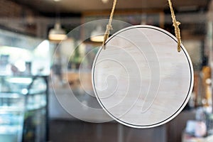 Blank vintage wooden sign board hanging on glass door in modern cafe restaurant, copy space for text advertising, advertisement ma