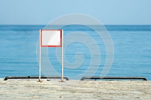 Blank warning sign by the sea on a sunny clear summer day