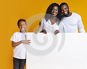 Blank white advertisement board in hands of happy black family