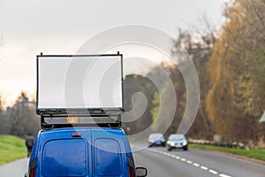 Blank white advertising banner sign on car roof next to UK motorway