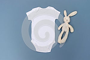 Blank white baby bodysuit grow mockup with cream rabbit soft toy on a light blue background