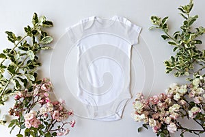 Blank White Baby Grow On An Off White Background With Green Leaves and Pink Roses photo