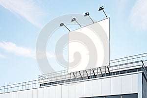 Blank white billboard outdoor with backlights from top on modern industrial building roof at blue sky background. 3D rendering,