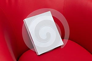 Blank white book hardcover on to top of a red sofa for mockup purpose