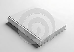 A blank white book lies on a plain surface casting a subtle shadow