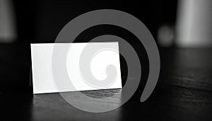 Blank white card on a dark textured surface in black and white paper empty