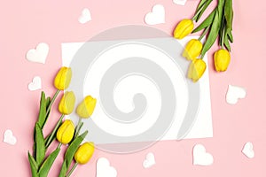 Blank white card with tulips flowers and hearts on pink pastel background. Flat lay, top view, copy space