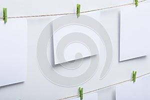 Blank white cards hanging on colored clothespins on a thread on a white background, a template for a photo collage, a concept of