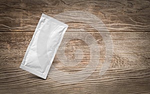 Blank White Condiment Packet Floating on Aged Wood Background