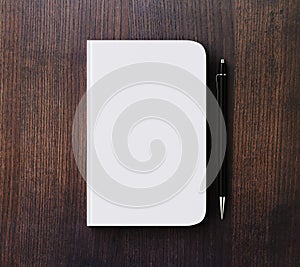 Blank white diary cover and pen on brown wooden table