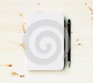 Blank white diary cover with pen on wooden table