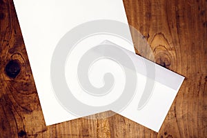 Blank white envelope and paper on wooden desk