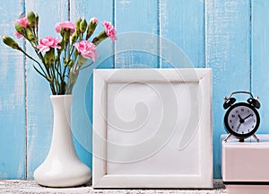 Blank white frame, pink flowers and alarm clock