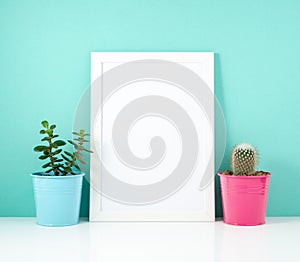 Blank white frame, plant cactus on white table against the blue wall. Mockup with copy space.