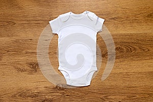 Blank white gender neutral babygrow onesie on a warm wooden background photo