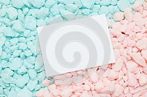 Blank white greeting card on blue and pink gravel background