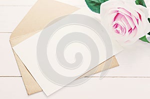 Blank white greeting card with brown envelope and purple rose